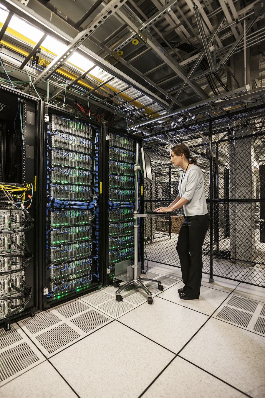 Caucasian woman technician working on computer servers in a server farm.